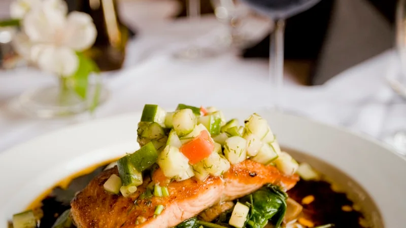 Pan-seared salmon fillet with herbs and lemon on a white plate